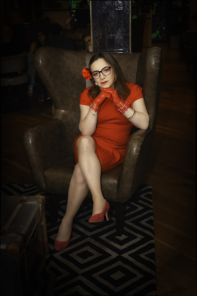 Annabelle in a red dress, seated at the hotel, getting ready for the evening