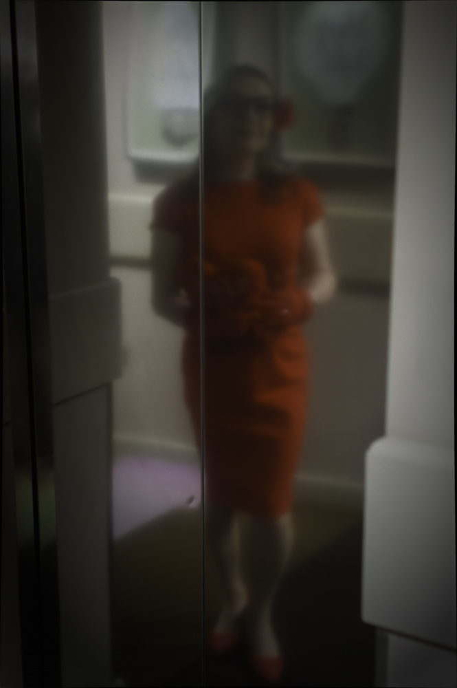 Annabelle in a red dress, reflected in the hotel lift doors