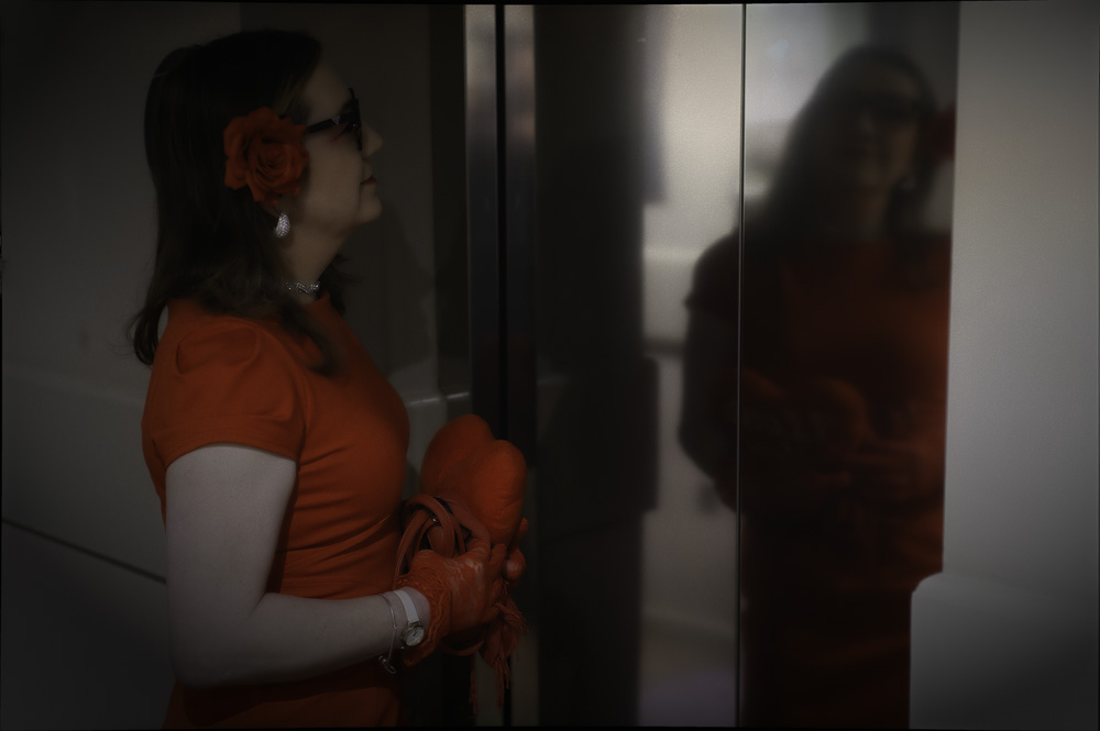 Annabelle in a red dress, reflected in the hotel lift doors