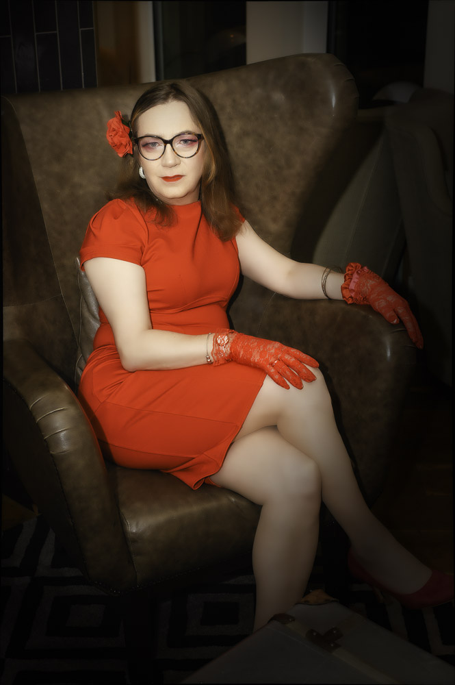 Annabelle in a red dress, seated at the hotel, getting ready for the evening