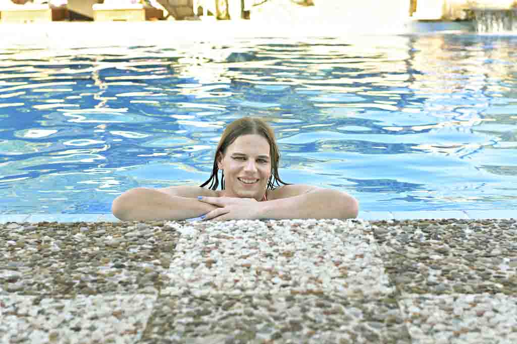 Daytime photo of Jessica in an orange bikini, arms resting on the edge of the pool, Zakynthos
